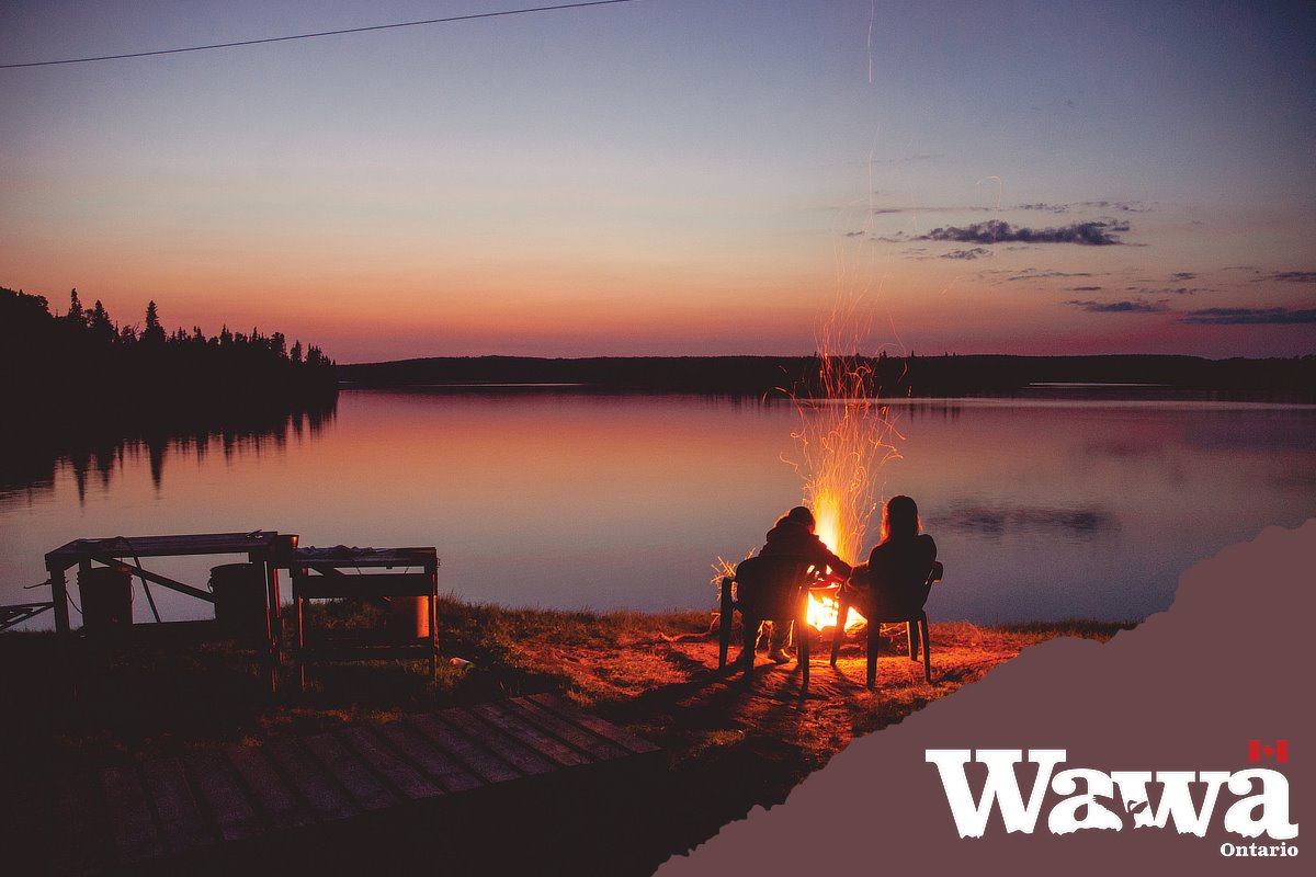 An image of two people sitting by a camp fire in Wawa.